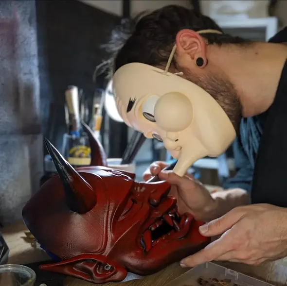 Jérémy peint un masque japonais Dai Yokai dans l'atelier