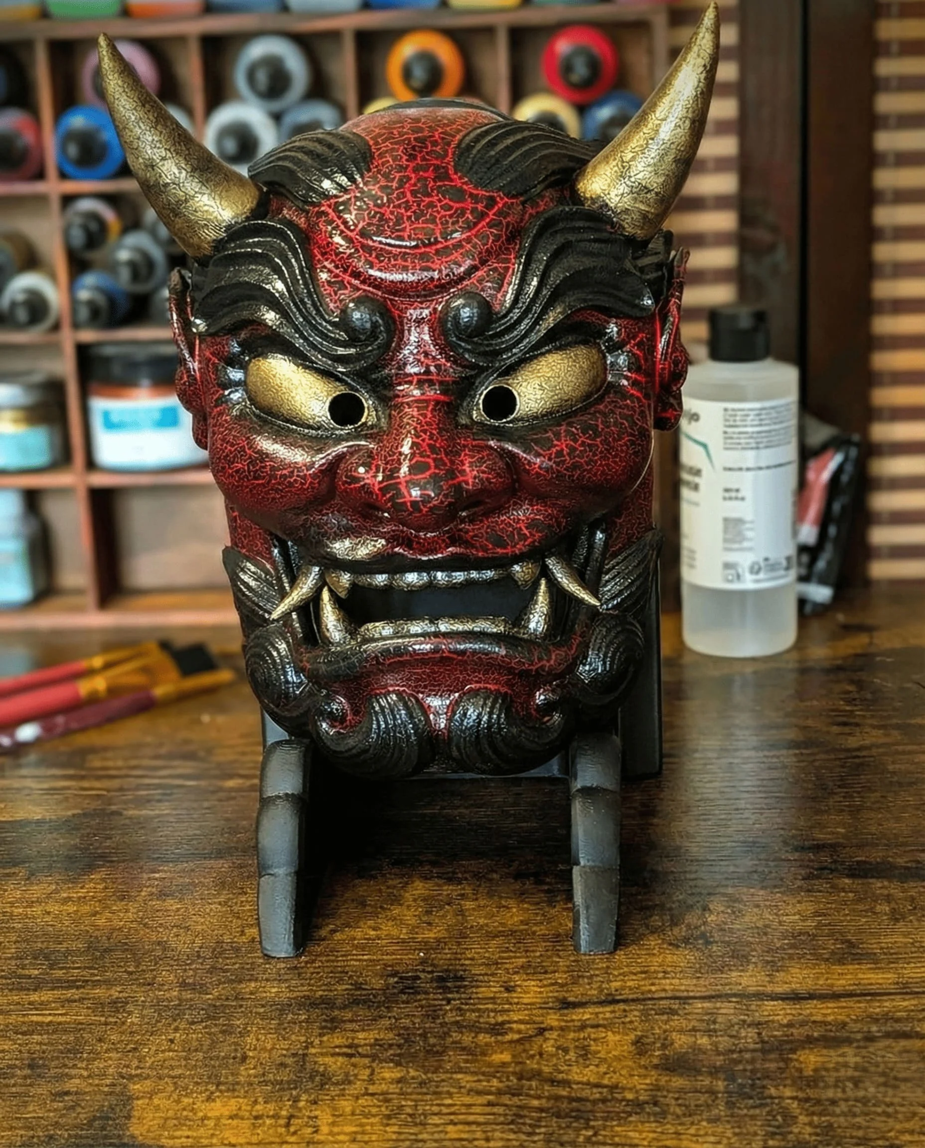 Masque Oni Gawara rouge craquelé, veines lave et cornes dorées peintes à la main