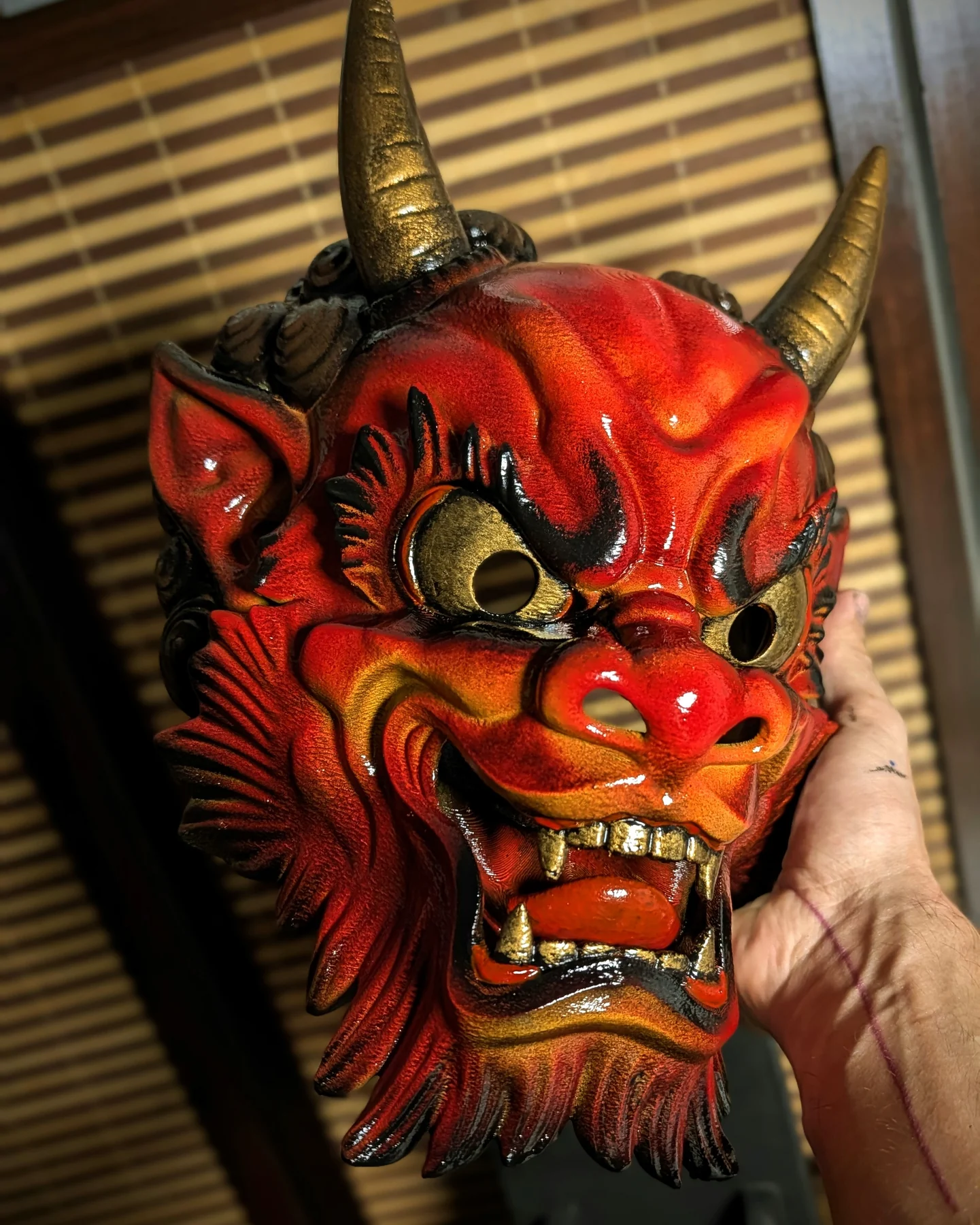 Handheld red Irezumi Oni Mask, showing the scale and glossy handmade finish.