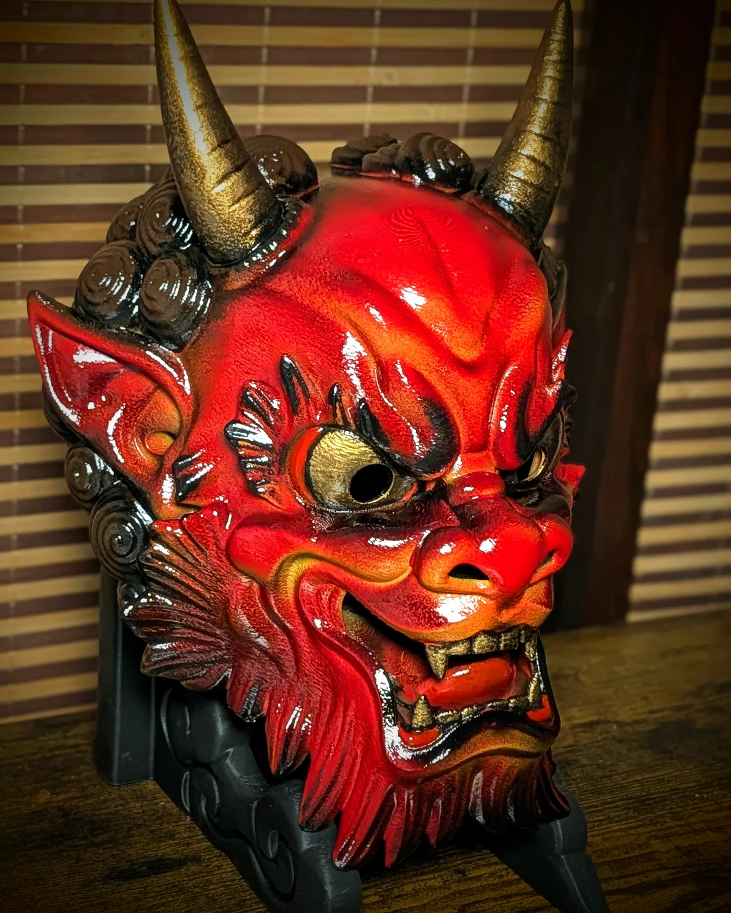 Three-quarter view of a handmade red Irezumi Oni Mask with gold horns and deep shadows.